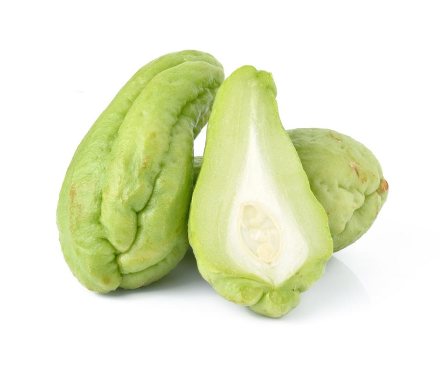 Fruit de la chouchoute (Sechium edule) entier et coupé en deux, montrant sa chair verdâtre et sa grosse graine unique © nipapornnan / iStock